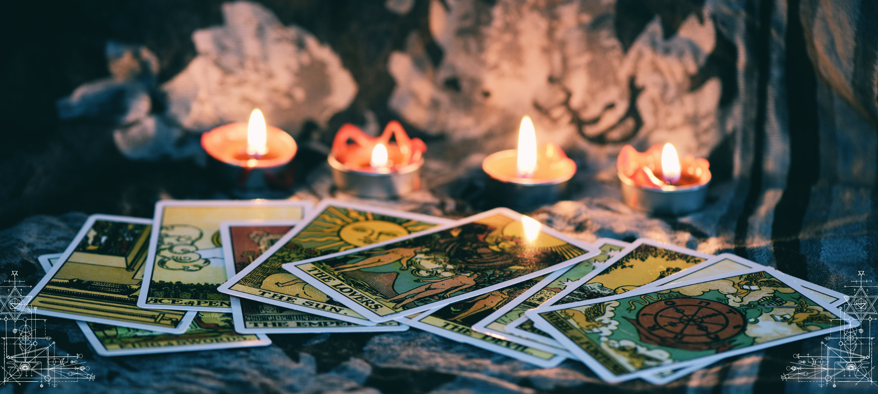 scattered tarot cards on a tabletop with 4 candles illuminating the image